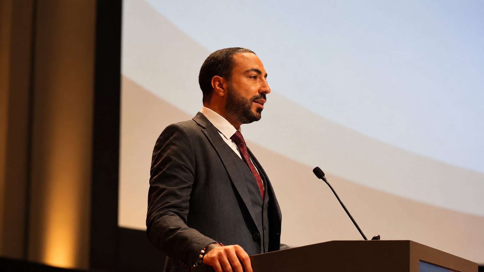Mümin Ahmedoğlu speaking at a podium